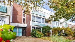 A modern apartment building with a brick facade, large windows, and a well-maintained garden area. - This one love - Cozy vacation apartment for up to 3 people in Alt (Sylt)