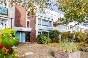 A modern apartment building with a brick facade, large windows, and a well-maintained garden area.