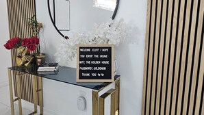 A modern reception desk with a black sign, a round mirror, and a decorative vase with flowers.