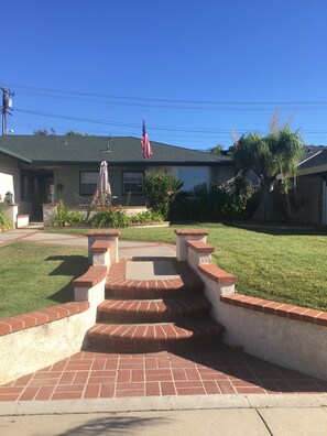 Ein Wohnhaus mit Vordergarten und einem Ziegelweg, der zum Eingang führt, sowie eine amerikanische Flagge.