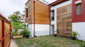 En moderne bygning med facade i træ, rødt tag og en belagt gårdsplads med plantekasser.