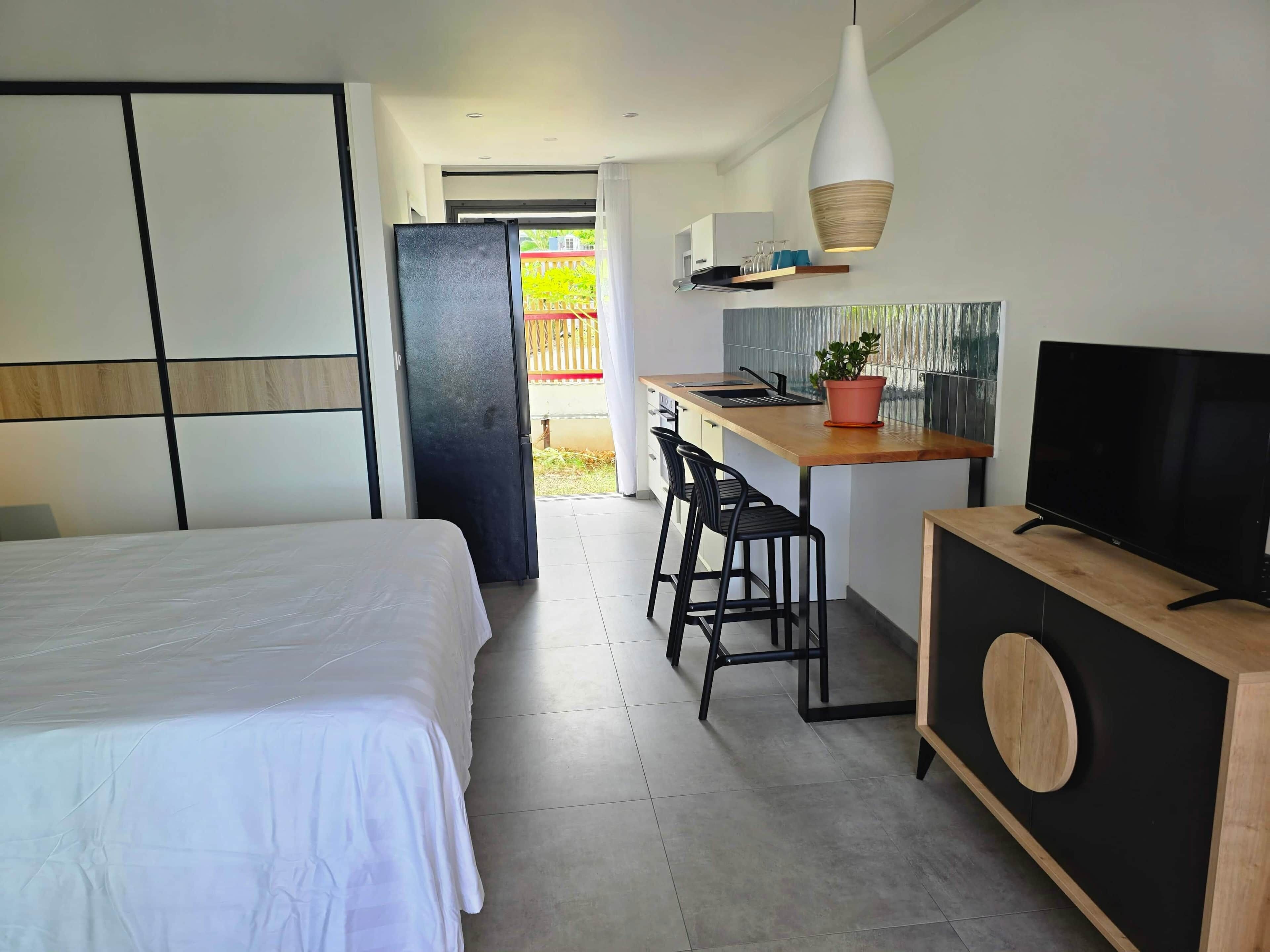 Une chambre d’hôtel moderne équipée d’un lit, d’une kitchenette, d’une télévision et d’un balcon.
