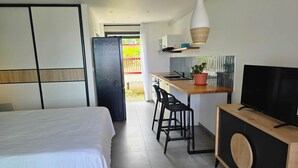 Et moderne hotelværelse med seng, tekøkken, fjernsyn og balkon.