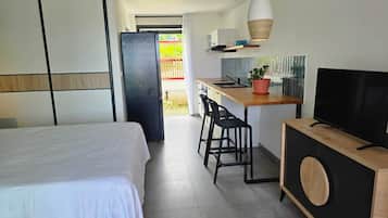 Une chambre d’hôtel moderne équipée d’un lit, d’une kitchenette, d’une télévision et d’un balcon.