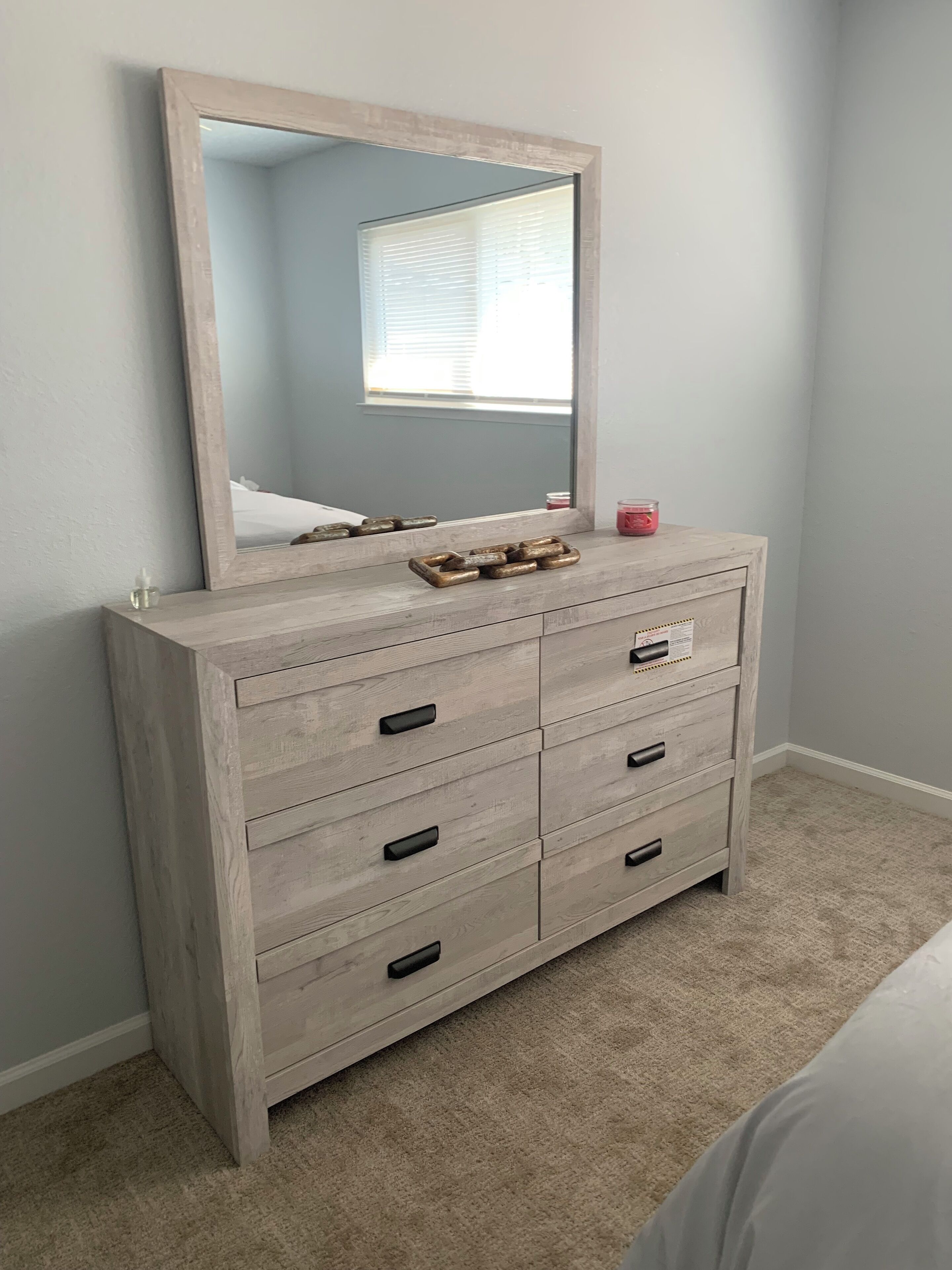 A wooden dresser with six drawers, a mirror above it, and a small candle on top.