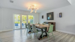 Un comedor moderno con una mesa de madera, sillas verdes y una lámpara de techo contemporánea.
