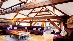 Ein geräumiger Loftsraum mit freiliegenden Holzbalken, Ledersofas und einem Holztisch.