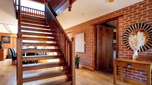 Eine Holztreppe in einem Raum mit Backsteinwänden und Holzdielen.