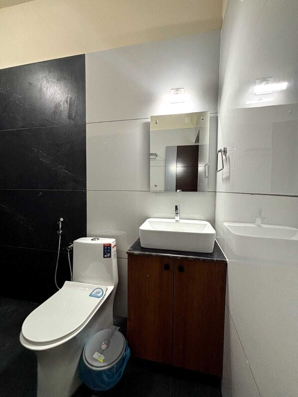 A modern bathroom with a toilet, sink, and mirror. - Evara Enclave Residency (Sullia)