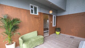 Een kamer met een groene bank, een kamerplant en een betegelde vloer.