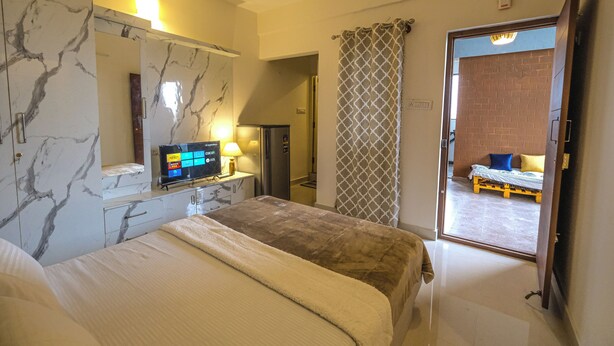 Hotelkamer met een bed, een televisie, een bureau met lamp en een badkamer die door een open deur zichtbaar is.