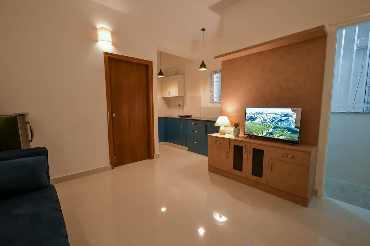 A modern living room with a flat-screen TV, a blue sofa, and a wooden cabinet.