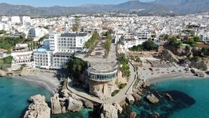 Ein Küstenhotel mit einer zentralen, kreisförmigen Struktur, umgeben von einer felsigen Küstenlinie und klarem, türkisblauem Wasser.