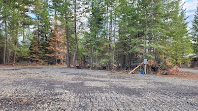 Large RV site with full hookups, surrounded by trees and nature.