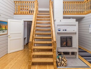 A wooden staircase leading to a loft area with a fireplace and a painting on the wall.