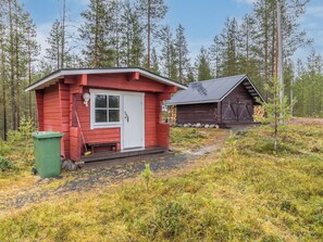 A red cabin with a white door and a small porch, surrounded by a forest. - Onnimanni by Interhome (Kuusamo)