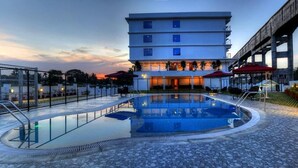 A hotel with a swimming pool, outdoor seating, and a view of a bridge. - The Atrium Boutique Hotel (Mysore)