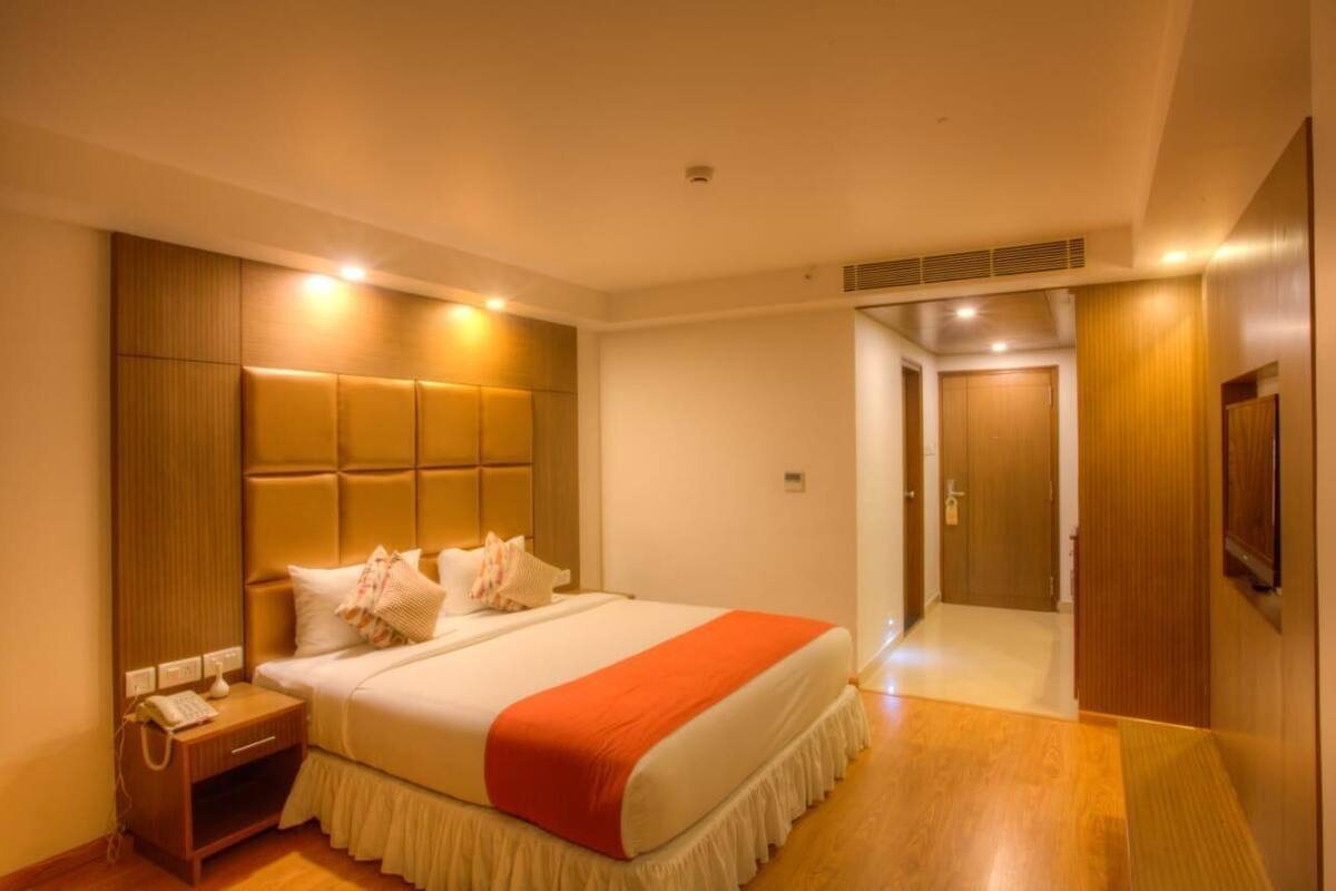 A hotel room with a large bed, wooden headboard, bedside table, and a telephone.