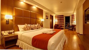 A hotel room with a large bed, bedside lamps, a desk with a telephone, and a view of the hallway. - The Atrium Boutique Hotel (Mysore)