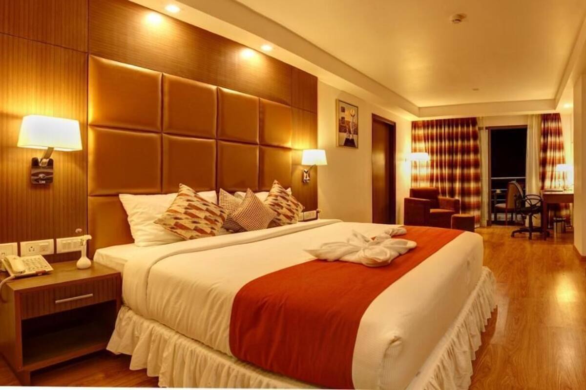 A hotel room with a large bed, bedside lamps, a desk with a telephone, and a view of the hallway.