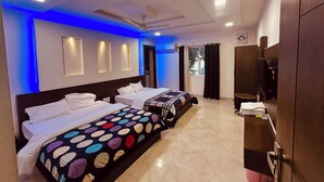 Ein Hotelzimmer mit zwei Betten, einem Kleiderschrank, einem Deckenventilator und einem Fenster mit Vorhängen.