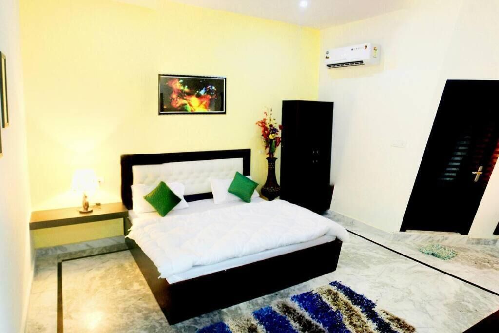 A bedroom with a bed, a nightstand, a wall-mounted air conditioner, and a door.