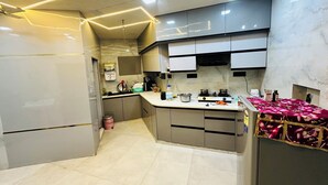 Eine moderne Küche mit grauen Schränken, einer Edelstahl-Arbeitsplatte und einer Marmor-Spritzschutzwand.