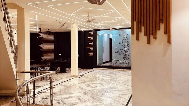 Eine großzügige Lobby mit Marmorboden, einem modernen Kronleuchter und einer Wand mit Holzakzenten.