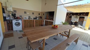 Uma cozinha com mesa de madeira, máquina de lavar e chão de azulejos.