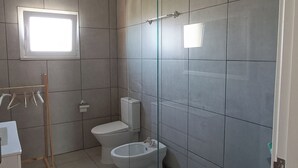 Um banheiro moderno com chuveiro, vaso sanitário, bidê e pia.