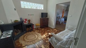 Uma sala de estar com lareira, TV, área de refeições com mesa e cadeiras, e piso estampado.
