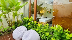 A modern outdoor seating area with a wooden deck, two white bean bags, and lush green plants.