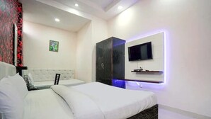 A modern hotel room with a large bed, a TV mounted on the wall, and a wardrobe. - Hotel Vishnu Residency Inn (Amritsar)