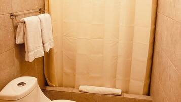 Un baño con inodoro, cortina de ducha y toallero con toallas.