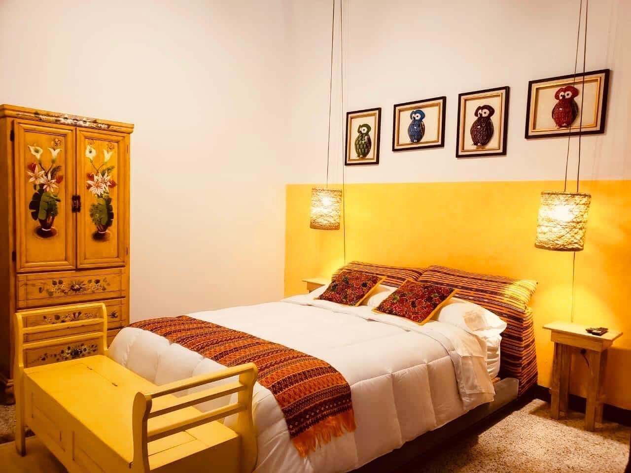 Um quarto com uma cama, uma cômoda de madeira e uma mesa de cabeceira.