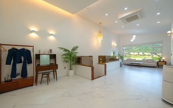 A modern hotel lobby with a reception desk, seating area, and a large window offering a view of the outdoors.