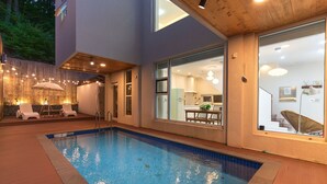 A modern house with a swimming pool, a dining area with outdoor furniture, and a kitchen visible through large windows. - Ulsan Byeoldam Eunchae Pool Villa (Ulsan)