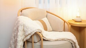 A cozy room with a round, cushioned seating area, a lamp, and a bedside table.