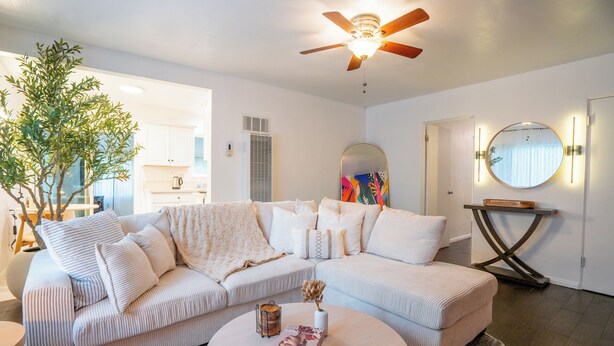 A modern living room with a sectional sofa, a round coffee table, and a ceiling fan.