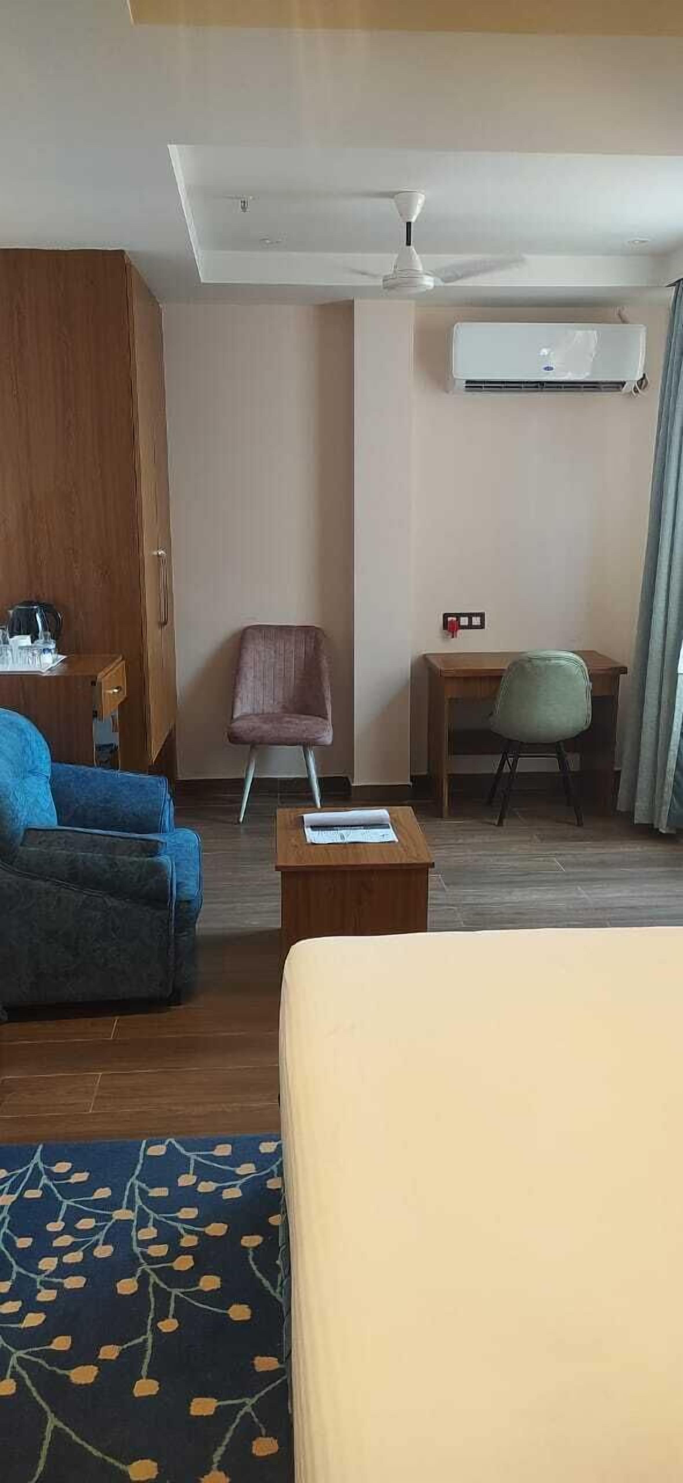 Quarto de hotel com cama, escrivaninha, cadeira, guarda-roupa e ar condicionado.