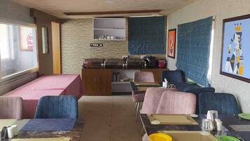 A dining area with a buffet setup, cushioned seating, and artwork on the walls.