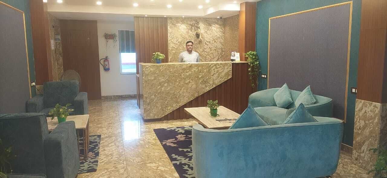 A hotel lobby with a reception desk, seating area, and a staircase.