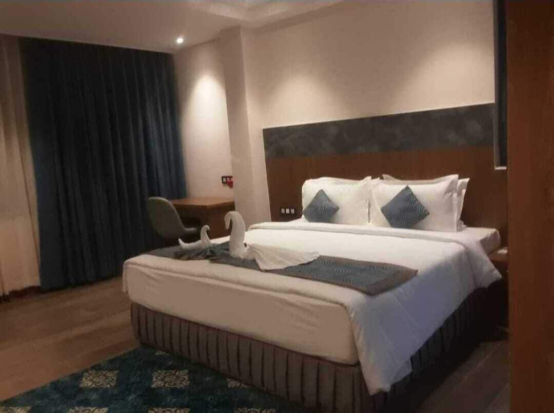 A hotel room with a large bed, a desk, and a chair.