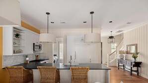 A kitchen with a central island, wicker chairs, and pendant lighting. - Wilson Cottages, Walk to Tennis & Pickleball, and Restaurants (Bluffton)