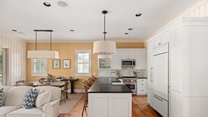A modern kitchen with white cabinetry, a central island, and pendant lighting. - Wilson Cottages, Walk to Tennis & Pickleball, and Restaurants (Bluffton)