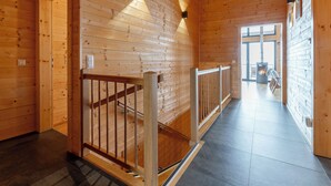 Un interior de madera con una escalera, una chimenea y vistas al exterior.