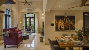A spacious living area with a purple sofa, a dining table set for two, and a large painting on the wall. - Luxury 3BR Duplex With Pool in Goa s Beverly Hills (Assagao)