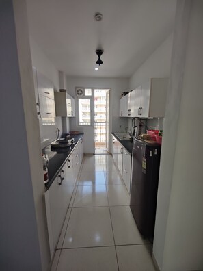 Een koelkast, een kookplaat, kookgerei, borden en bestek