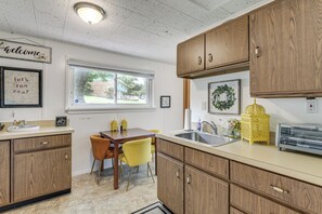 A kitchen with wooden cabinets, a dining table with chairs, a window, and a welcome sign. - 3 Mi to Dtwn Silver Spring: Convenient DC Area Apt (Silver Spring)