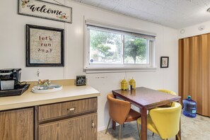 A room with a dining table, chairs, a coffee machine, a water dispenser, and a window with a view of trees. - 3 Mi to Dtwn Silver Spring: Convenient DC Area Apt (Silver Spring)